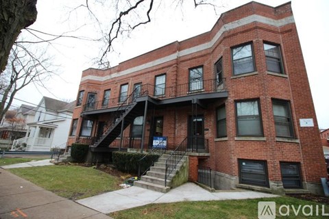 A red brick building with a black railing on the balcony.