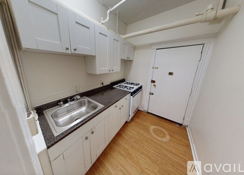A kitchen with white cabinets and a wooden floor.