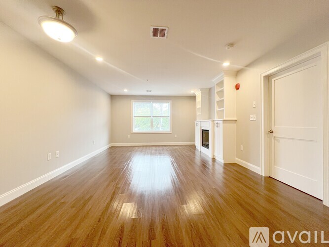 A spacious room with wooden floors and white walls.