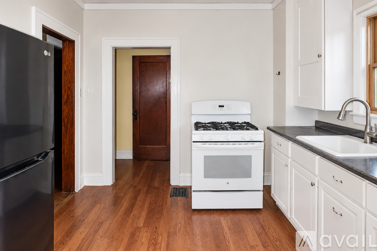 A kitchen with a black fridge, white stove and wooden floors.