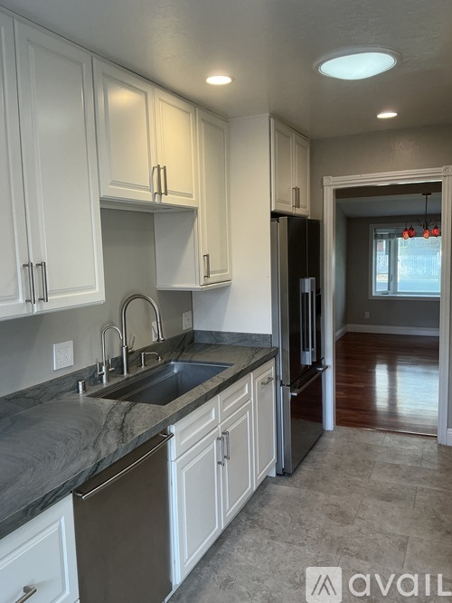 A kitchen with white cabinets and a black refrigerator.