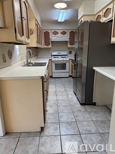 A kitchen with a black refrigerator and white countertops.