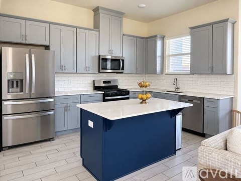 A kitchen with a blue island and stainless steel appliances.