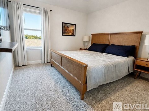 A bedroom with a large bed and a window overlooking a field.