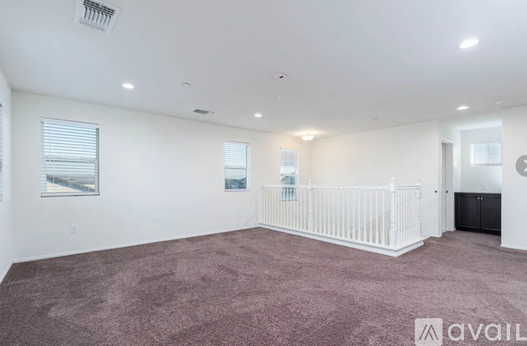A spacious room with a white ceiling and a carpeted floor.