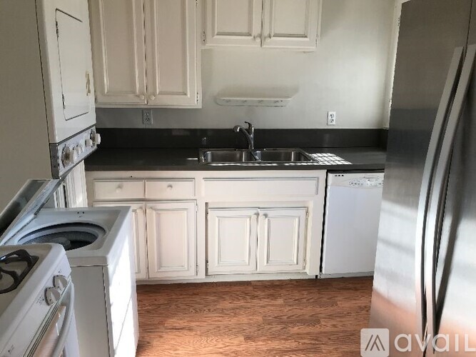 A kitchen with white cabinets and a black countertop.