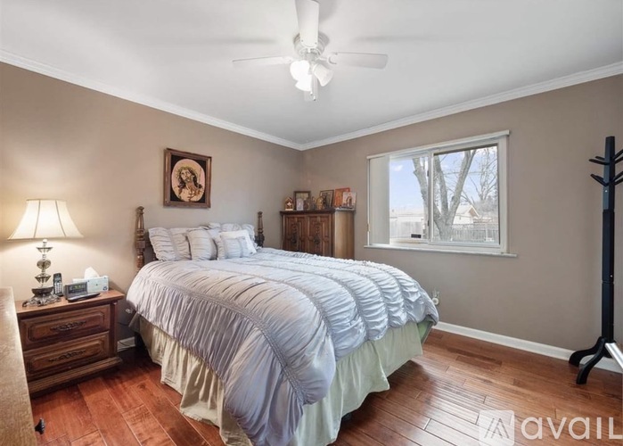 A bedroom with a large bed and a window showing trees outside.