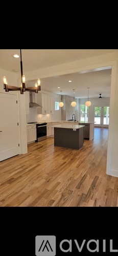 A modern kitchen with wooden floors and white walls.