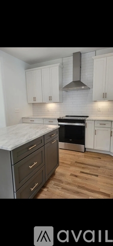 A kitchen with white cabinets and a wooden floor.