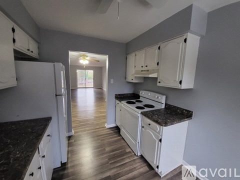 A kitchen with white cabinets and a black countertop.