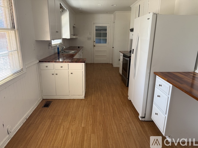 A kitchen with white cabinets and a wooden floor.