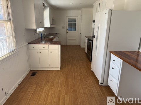 A kitchen with white cabinets and a wooden floor.