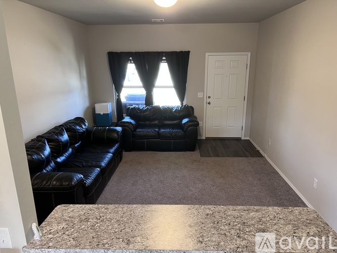 A living room with a black leather couch and a granite countertop.