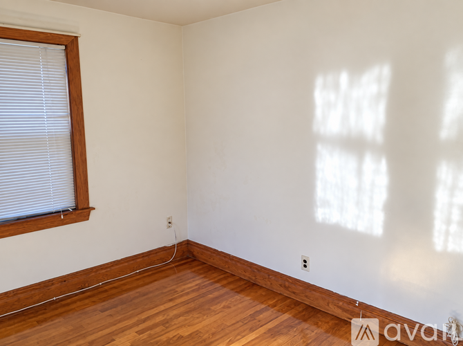 A room with wooden floors and a window with blinds.