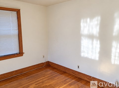 A room with wooden floors and a window with blinds.