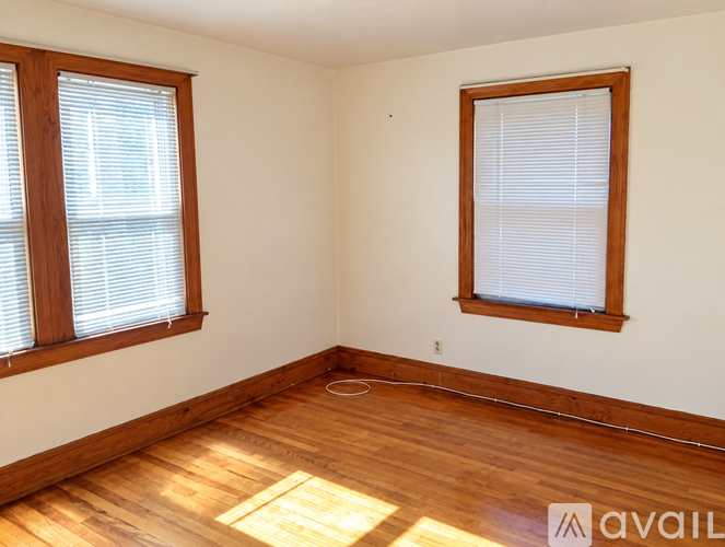 A room with wooden floors and two windows.