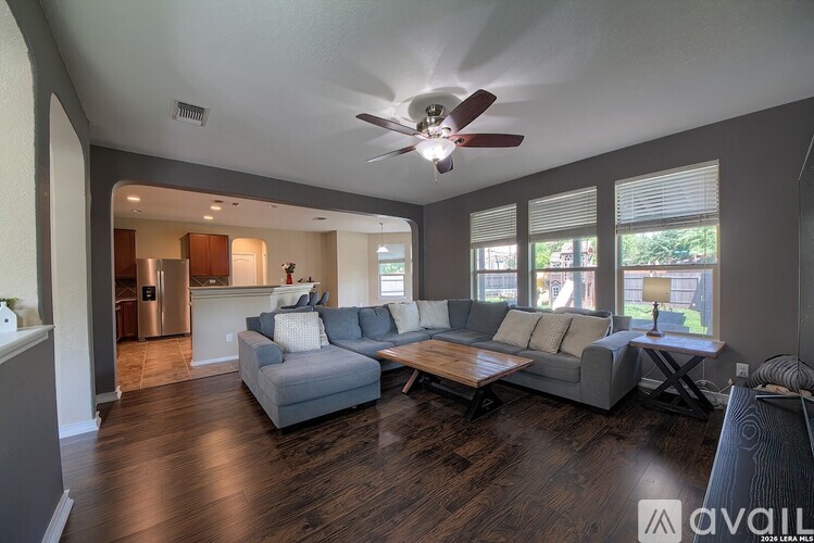 A living room with a grey couch and a wooden floor.
