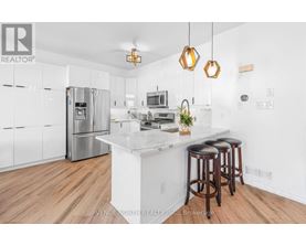 A modern kitchen with wooden floors and a white island.