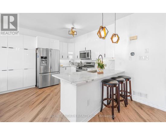 A modern kitchen with wooden floors and a white island.