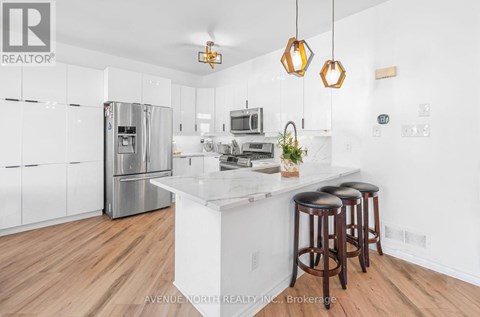 A modern kitchen with wooden floors and a white island.