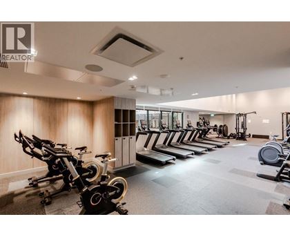 A gym with a row of stationary bikes and a row of treadmills.