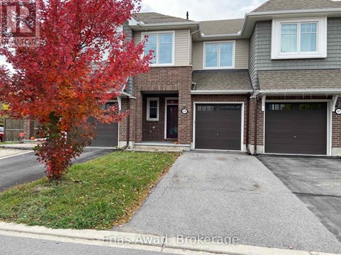 A red tree in front of a grey house.