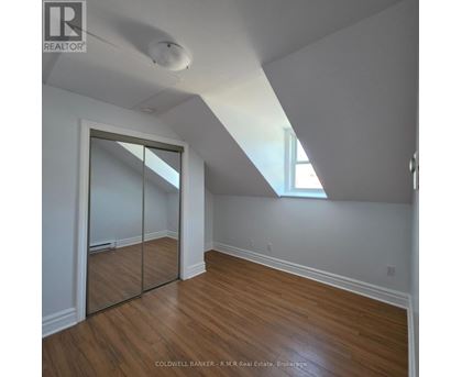 A room with wooden floors and a slanted ceiling.