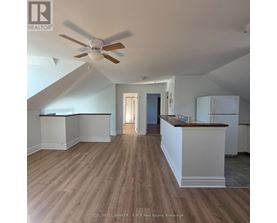 A spacious room with a ceiling fan and wooden flooring.