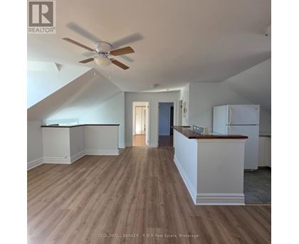 A spacious room with a ceiling fan and wooden flooring.