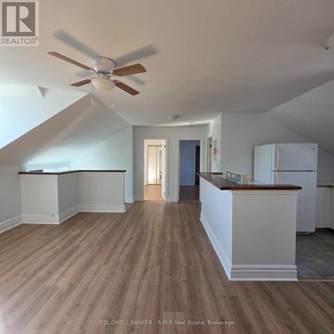 A spacious room with a ceiling fan and wooden flooring.