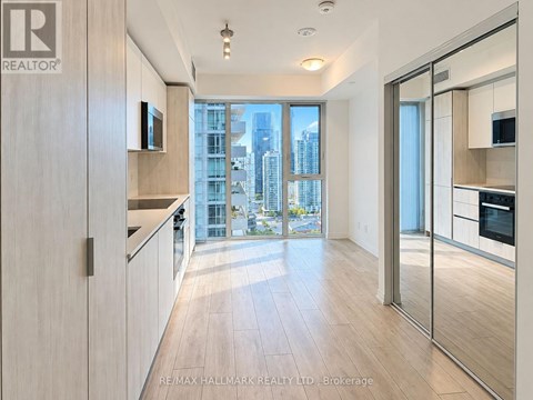 A modern kitchen with wooden floors and a large window overlooking the city.