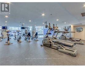 A gym with a row of treadmills and elliptical machines.