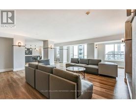 A spacious living room with a grey sofa set and a glass table.