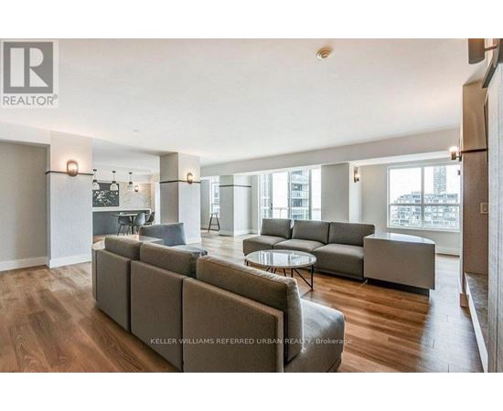 A spacious living room with a grey sofa set and a glass table.