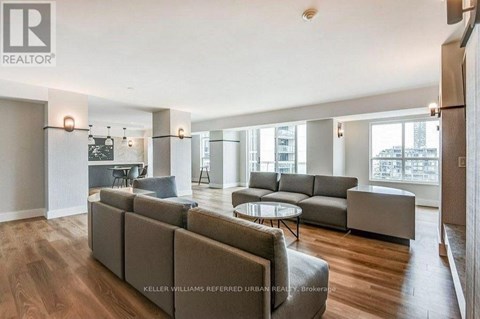 A spacious living room with a grey sofa set and a glass table.