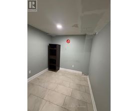 A room with a wooden cabinet and a red fire alarm on the wall.