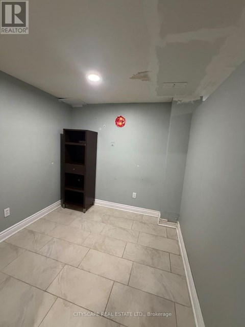 A room with a wooden cabinet and a red fire alarm on the wall.