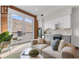 A living room with a couch, a chair, and a potted plant.