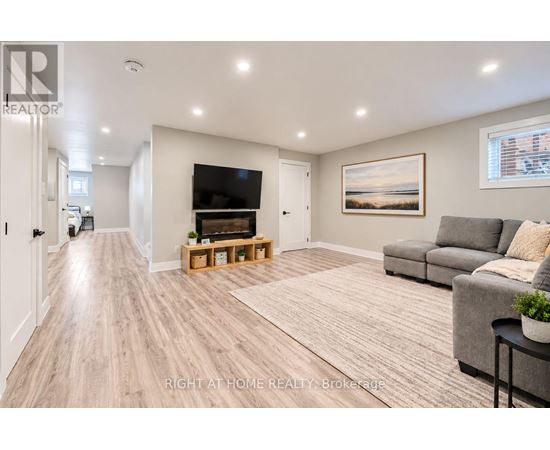 A spacious living room with a grey couch and a wooden floor.