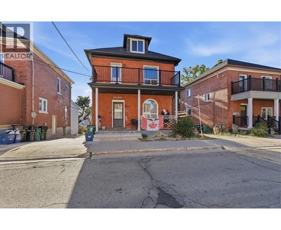 A red brick house with a black balcony and a small porch.