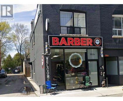 A barber shop with a sign that reads "Barber" and a clock on the sign.