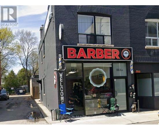 A barber shop with a sign that reads "Barber" and a clock on the sign.