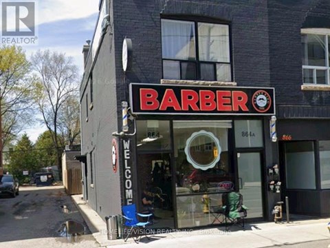 A barber shop with a sign that reads "Barber" and a clock on the sign.