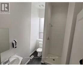 A white bathroom with a sink, toilet, and shower.