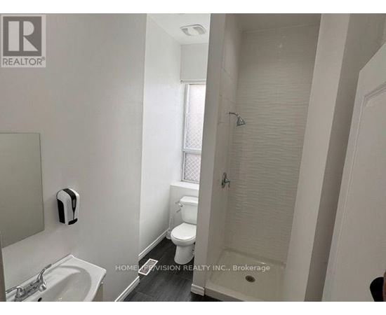 A white bathroom with a sink, toilet, and shower.