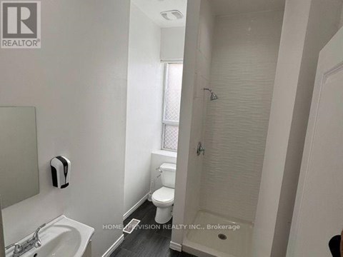 A white bathroom with a sink, toilet, and shower.