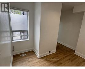 A room with a window and wooden flooring.