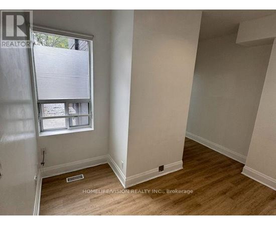 A room with a window and wooden flooring.