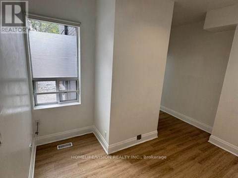 A room with a window and wooden flooring.