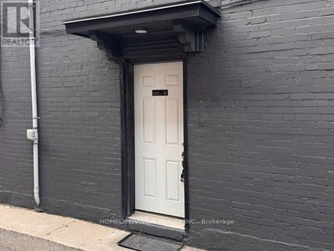 A white door is set in a black brick wall.